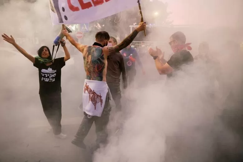 HUMO. Manifestantes gritan consignas durante una protesta contra la supuesta corrupción del primer ministro israelí Benjamin Netanyahu. fotos reuters