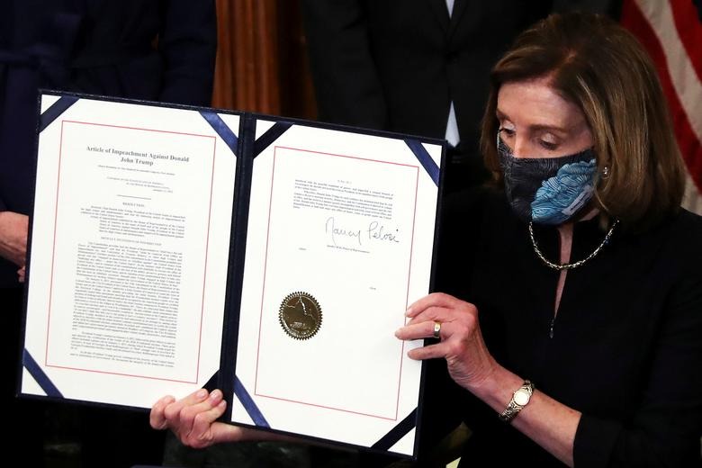 JUICIO POLÍTICO. La presidenta de la Cámara de Representantes de Estados Unidos, Nancy Pelosi, muestra el artículo de acusación contra el presidente Trump después de firmarlo en una ceremonia que resultó rápida.