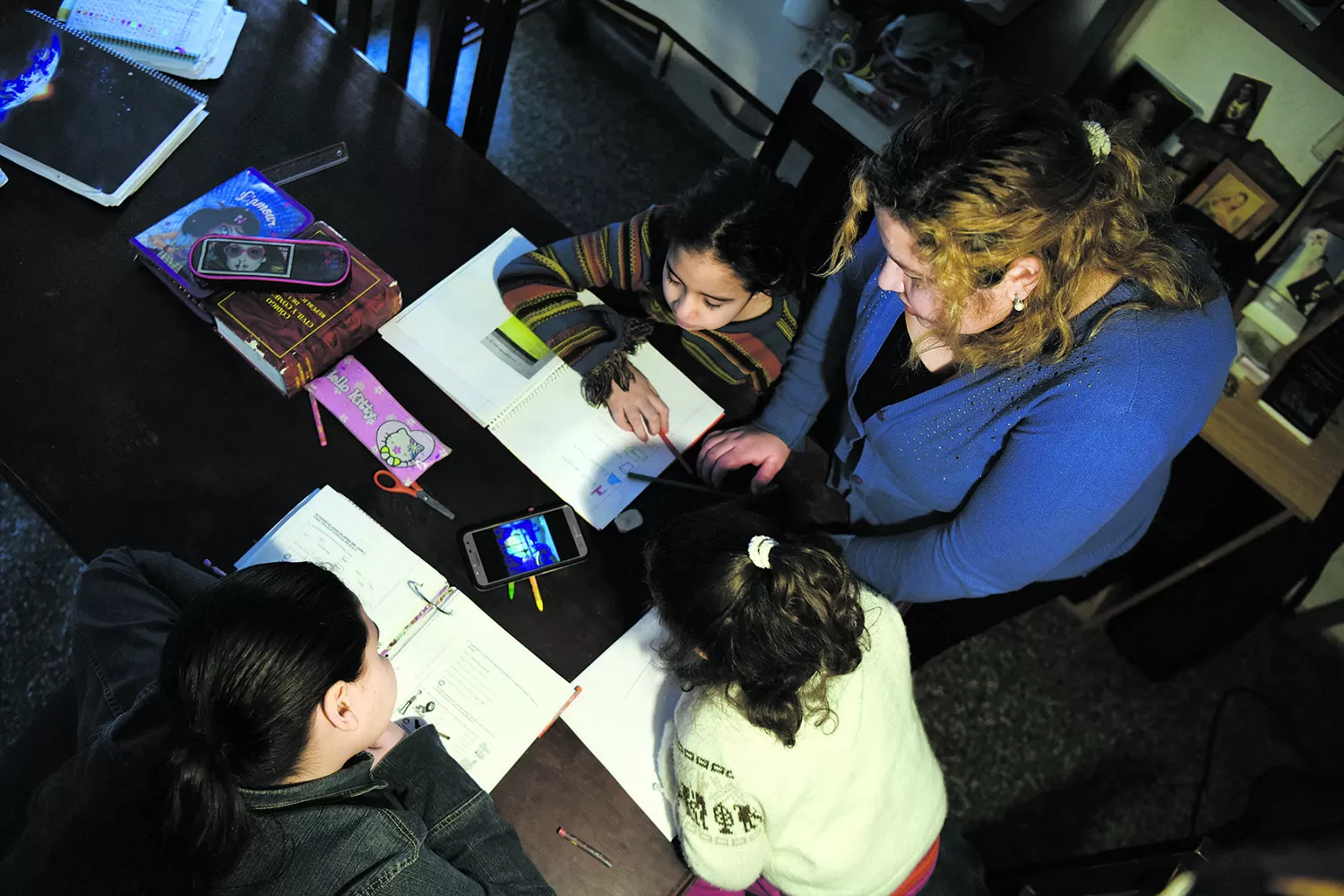 MAMÁ EN PLENA TAREA. Enseña a sus hijas con apoyo del celular.