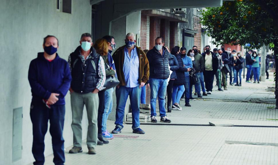 FILA. La gente esperó para vacunarse en la vereda del club Caja Popular. 