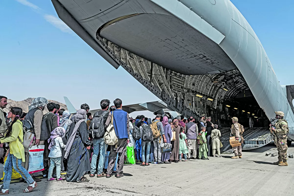 EVACUADOS. Marines guían a afganos bajo protección especial para que suban a un avión militar estadounidense en el aeropuerto de Kabul.