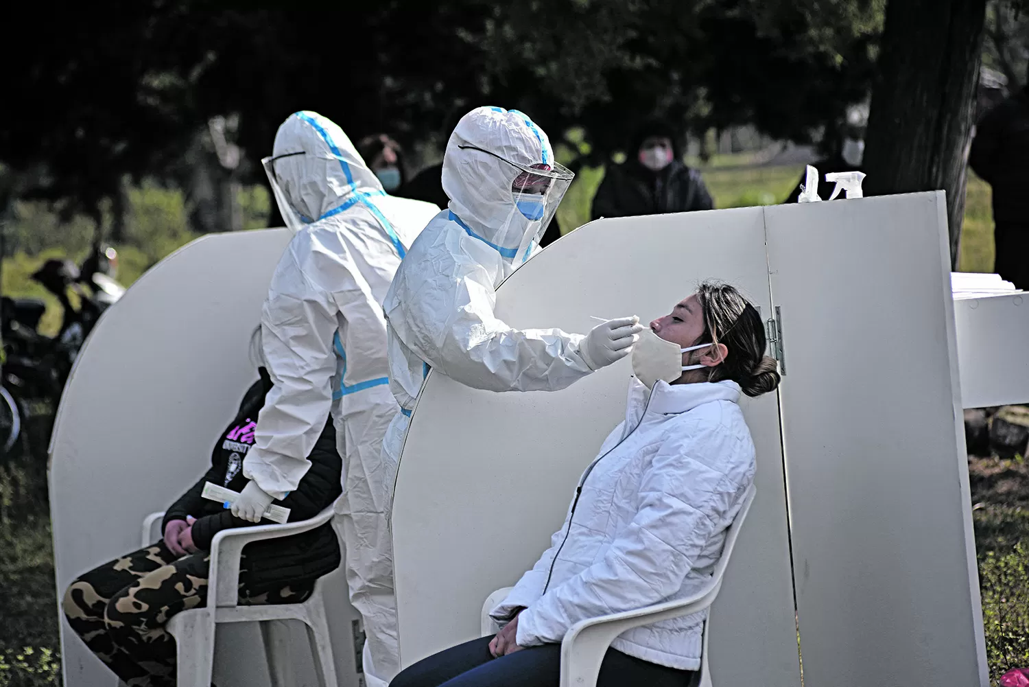 HISOPADOS. Dos enfermeros hisopan a ciudadanos en un proceso de testeo en la vía pública.