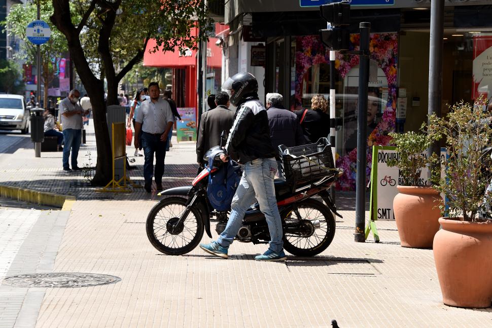 ¿ESTÁ BIEN O MAL? El cadete empuja su moto para no generar riesgo a transeúntes, pero ocupa espacio estrictamente peatonal.