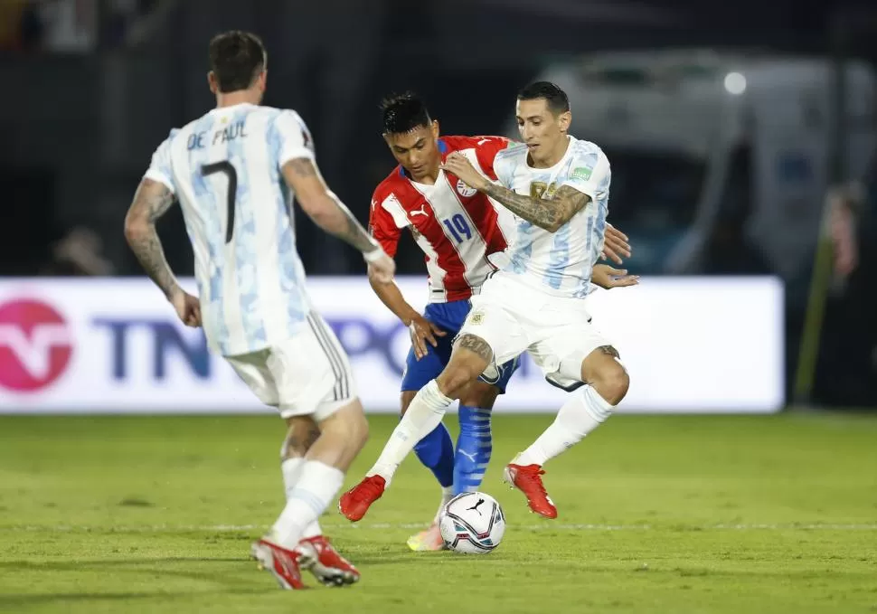 MARCA A PRESIÓN. Ángel Di María intenta llevarse la pelota, asediado por la marca del lateral izquierdo Santiago Arzamendia. Rodrigo De Paul contempla la jugada desde cerca. 