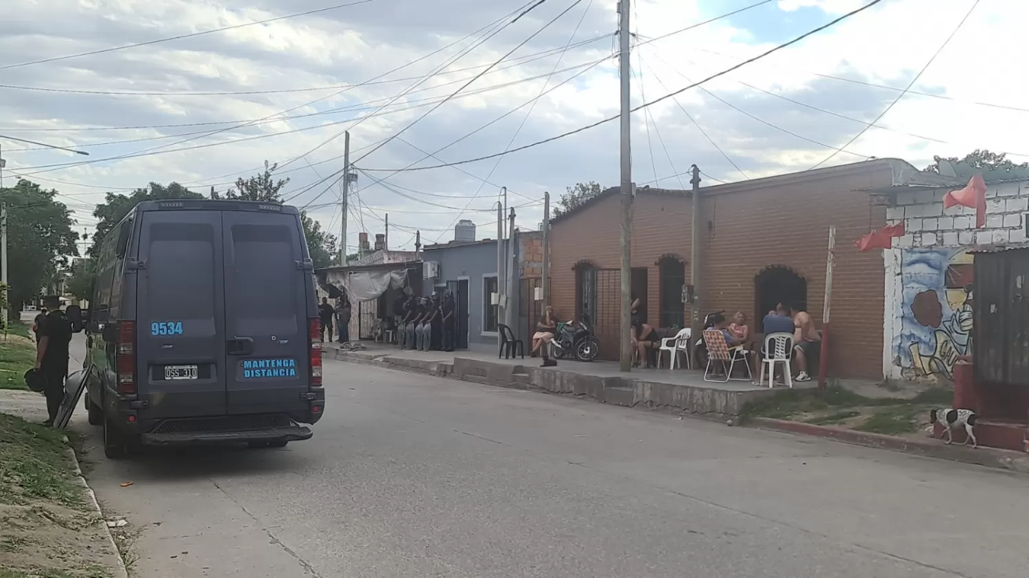 EL CALOR PUEDE más que el miedo. Los vecinos siguen en sus reposeras, mientras la policía allana la casa de al lado. 