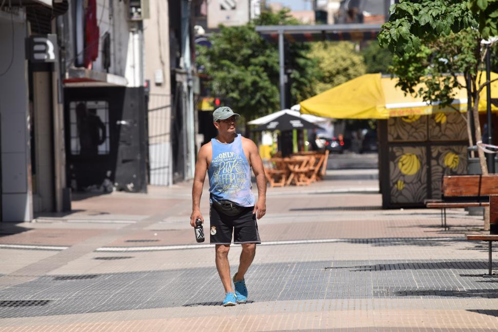 SOLO EN LA PEATONAL. Un hombre se desplaza entre comercios cerrados con gorra y agua, y sin barbijo.