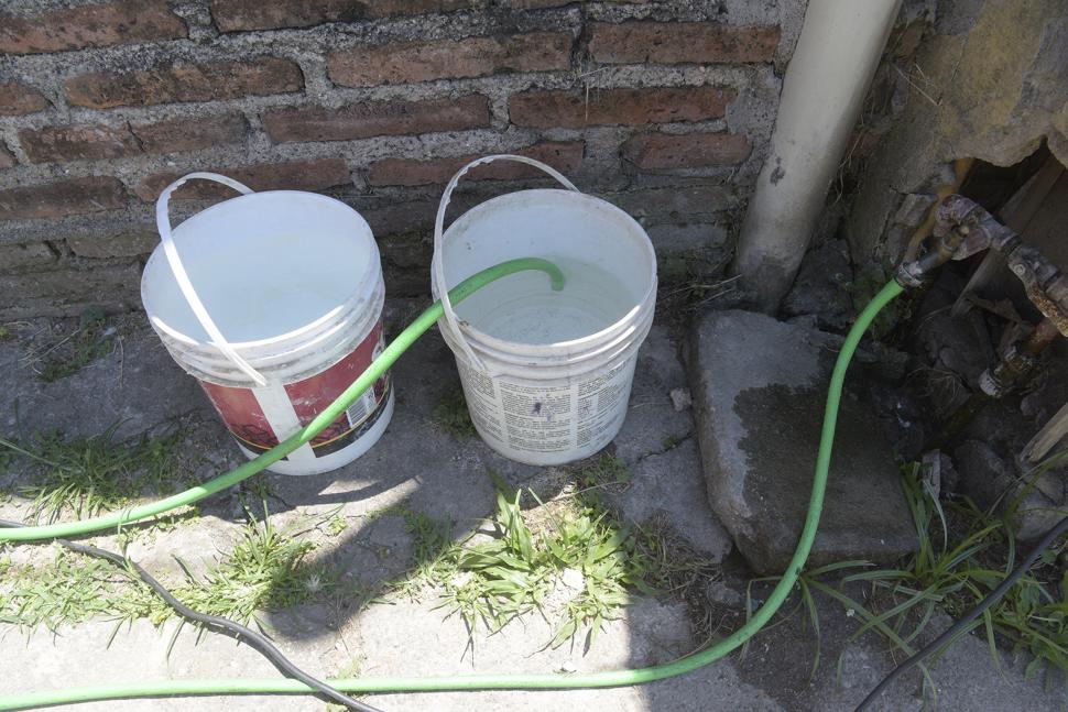 EN BALDES DE PLÁSTICO. En estos recipientes, los pobladores juntan agua para llevar a sus casas, un elemento que escasea en verano para sus pesares.  