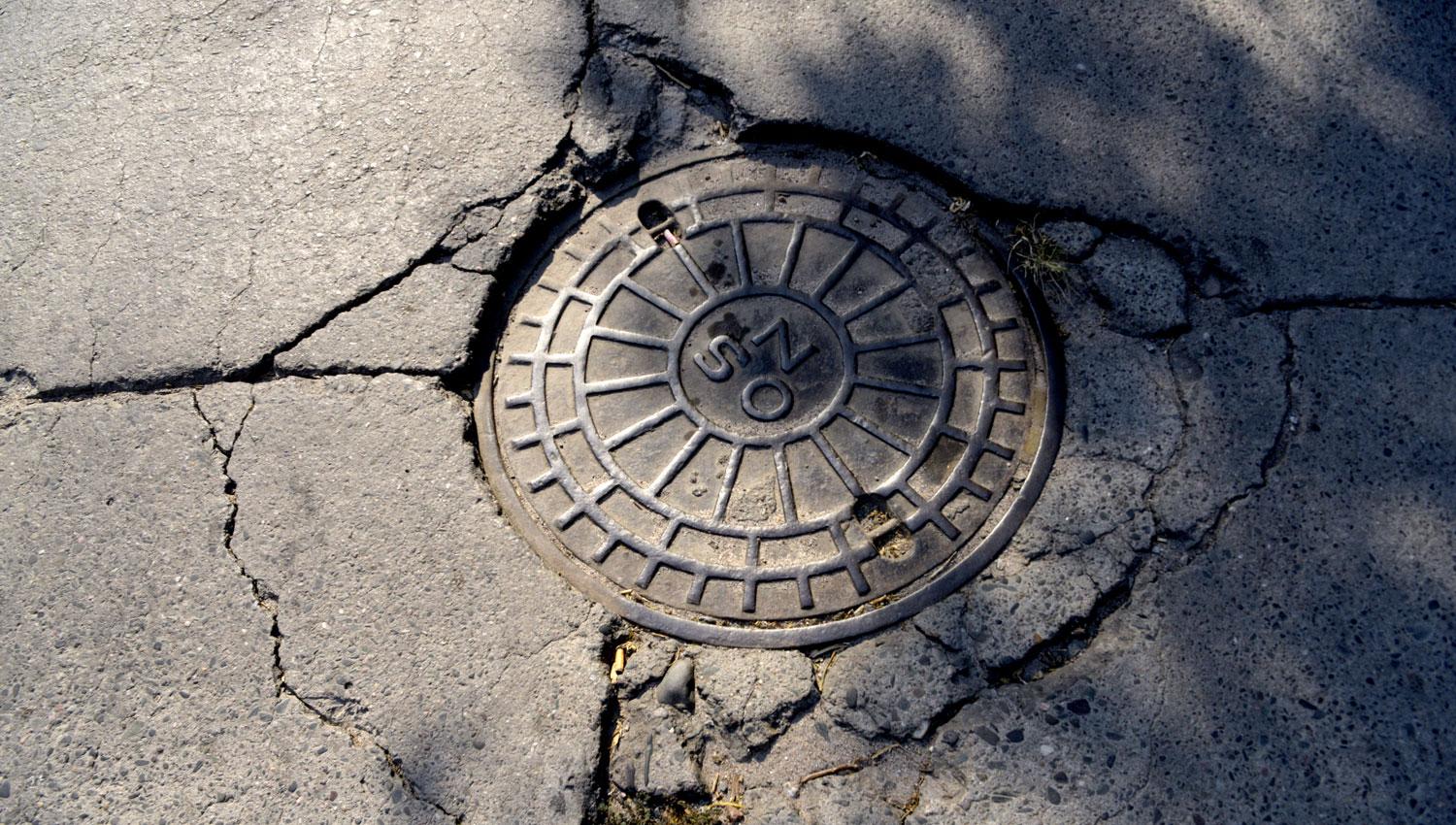 A PUNTO DE COLAPSAR. Las grietas alrededor de esta tapa, en San Juan al 3.900, parecen presagiar un inminente hundimiento.