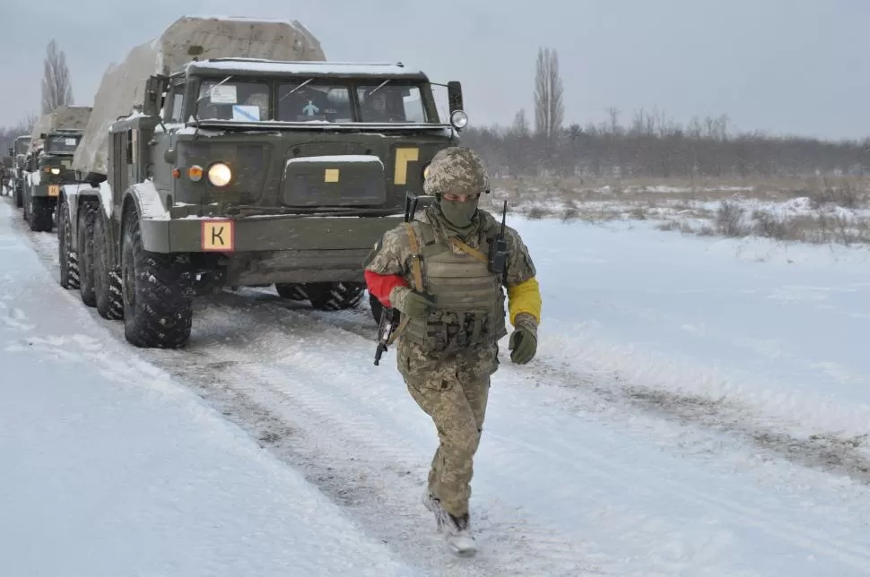 EJERCICIO. Un soldado ucraniano camina en medio de la nieve frente a un convoy de vehículos pesados, en medio de una maniobra en la frontera. 