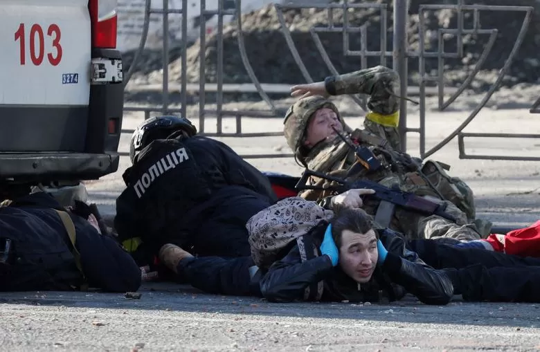 La gente se pone a cubierto cuando suena una sirena de ataque aéreo, cerca de un edificio de apartamentos dañado por los recientes bombardeos en Kiev, Ucrania, el 26 de febrero.