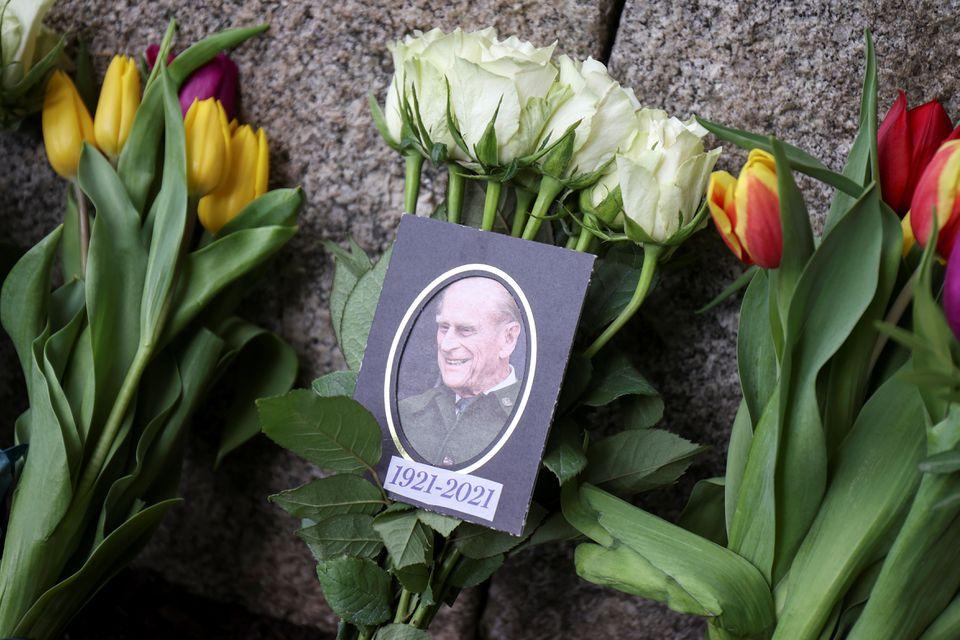 Una foto del príncipe Felipe de Gran Bretaña, esposo de la reina Isabel, quien murió a la edad de 99 años, se ve entre las flores fuera del castillo de Windsor, en Windsor, cerca de Londres. (Reuters)