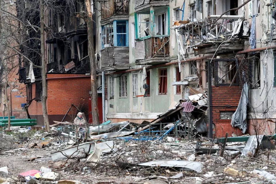 Un residente local se sienta en un banco en un patio dañado durante el conflicto Ucrania-Rusia en la ciudad portuaria sureña de Mariupol. (Reuters)