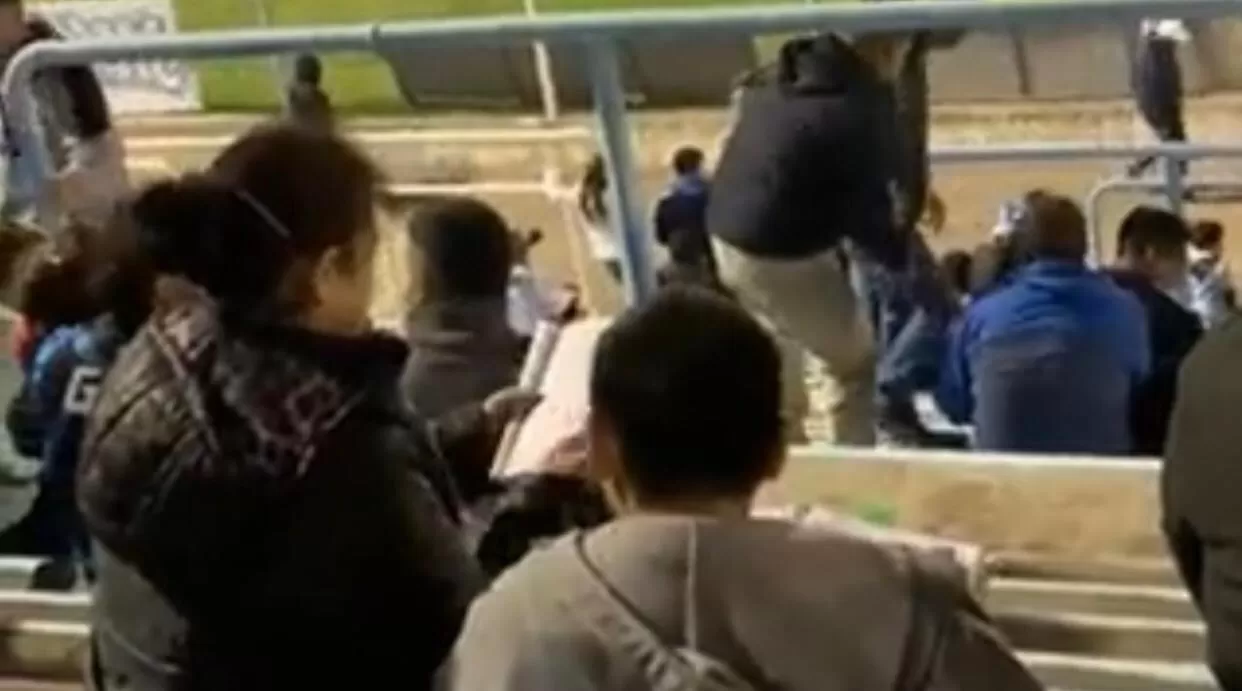 El niño y la mujer que lo acompañaba, haciendo la tarea en la cancha de Gimnasia y Tiro.