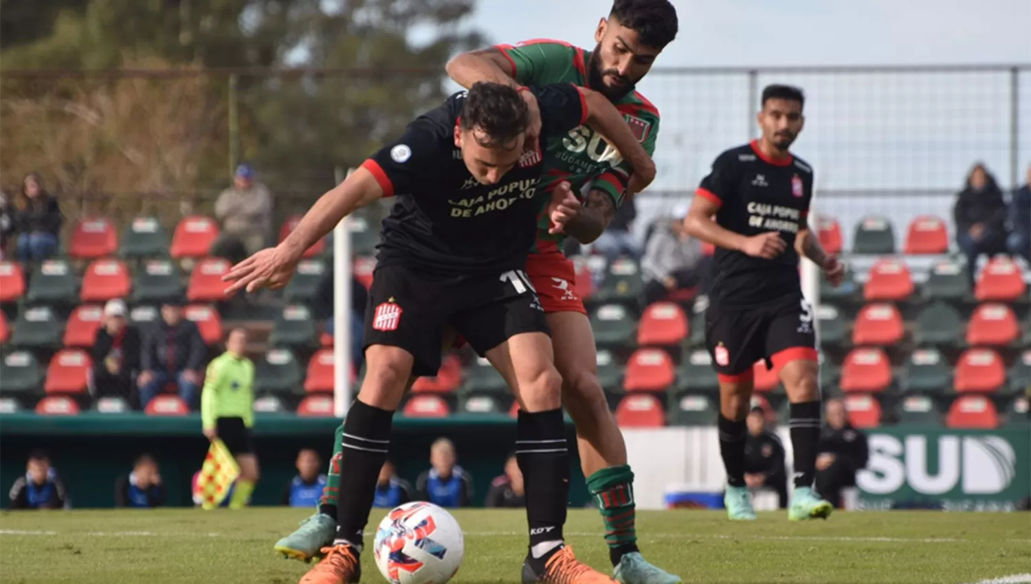 PRESIÓN. Valentín Larralde aguanta la pelota ante la marca de Emanuel Dening y la mirada de Rodrigo Herrera.