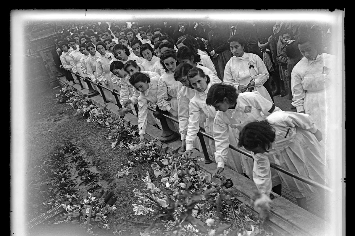 LOS CHICOS Y LAS FLORES. Se aprecia cómo las alumnas llevan brazaletes o crespones o negros. Fue obligatorio portarlos mientras se mantuvo el duelo nacional.