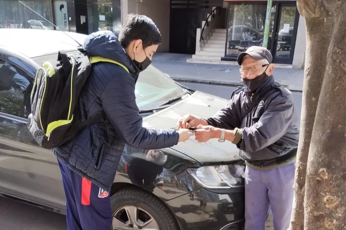 AYUDA. Un estudiante le ofrece un alfajor a un jubilado. 