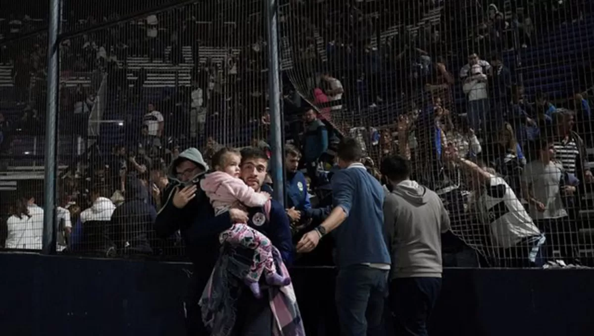 AUXILIO. Un hincha junto a su pequeña hija busca ingresar al campo para poder escapar del humo de los gases arrojados contra la tribuna.