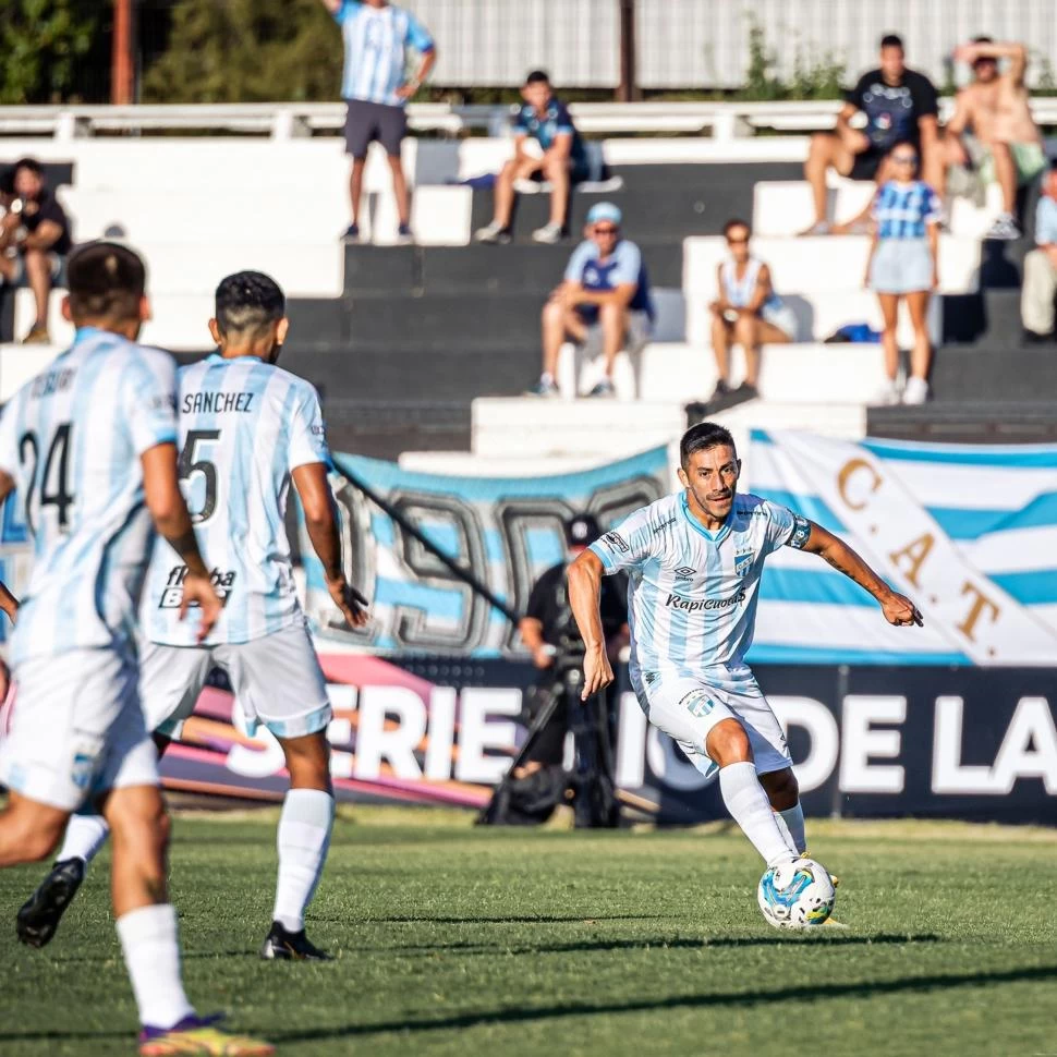 PRESENTES. Acosta maneja la pelota y de fondo algunas banderas “decanas”. 