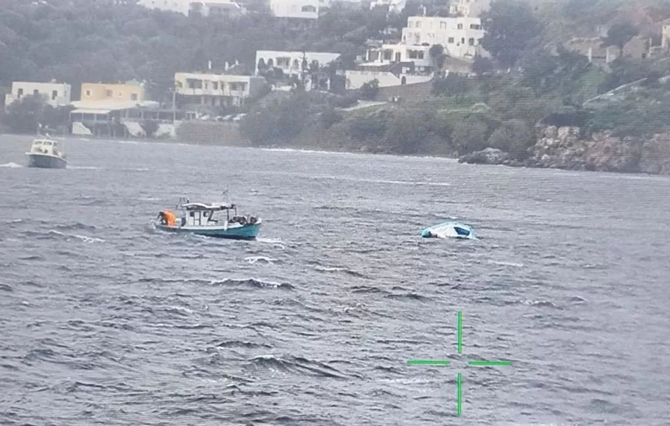 Un barco de pesca se acerca a un bote inflable medio hundido que transportaba inmigrantes fuera de la isla de Leros, Grecia, el 5 de febrero de 2023. Guardia Costera Helénica
