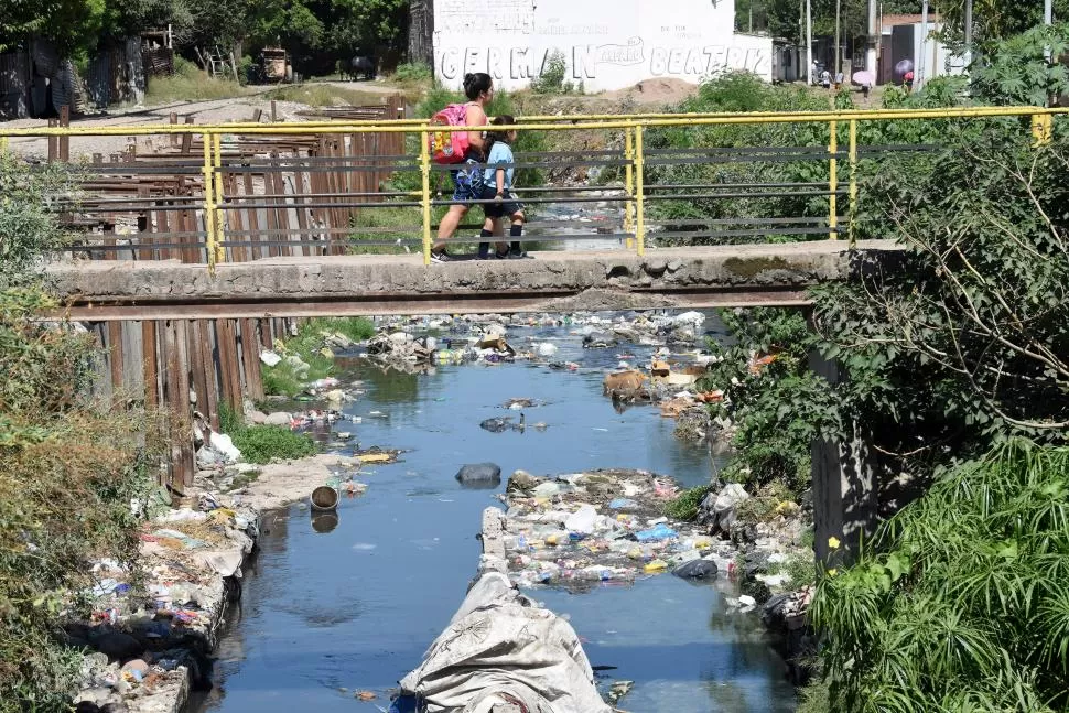 PELIGRO. Vecinos culpan al canal de las infecciones de dengue en el barrio ex Ingenio Amalia; diariamente usan el puente para sus traslados. 