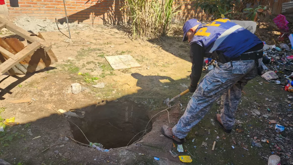 Un federal busca la droga en un pozo. 