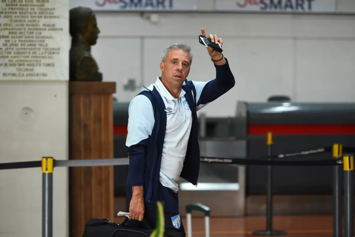 MUY TRANQUILOS. Lucas Pusineri (arriba) saluda a la distancia a un hincha. Mientras tanto, los jugadores (foto de abajo) compartieron mates en la confitería del aeropuerto, con el partido entre Belgrano y Vélez de fondo.