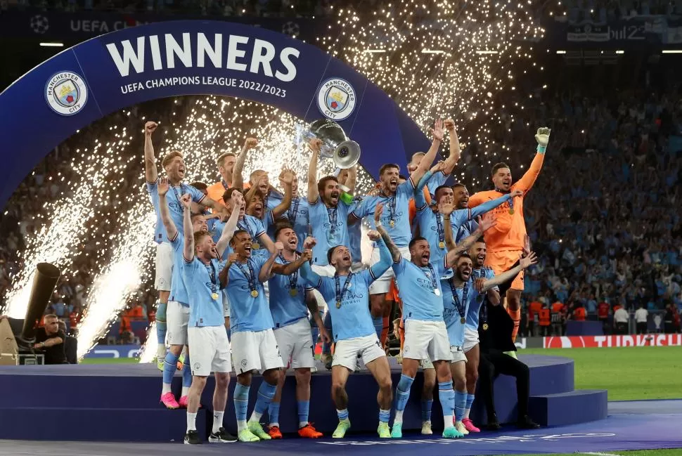 LA FOTO ESPERADA. El plantel de Manchester City posa con el trofeo más importante a nivel clubes de Europa. Guardiola se dio el gusto de conseguir el título después de 14 años; tercera “orejona” para él. reuters