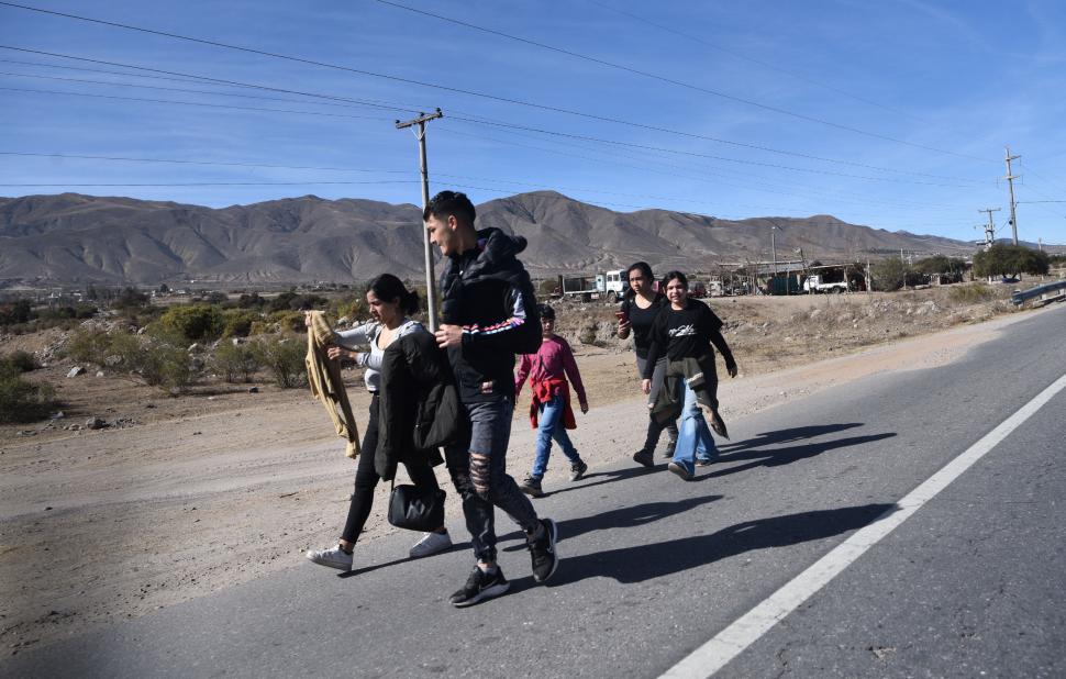 Las postales de familias caminando a la vera de la ruta son comunes.