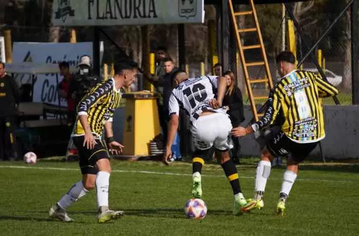 PRESIONADO. Rivadero (Flandria) pisa la pelota ante una doble marca.   