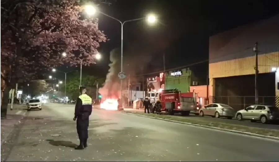El taxi, en llamas. Los bomberos sofocan el incendio. 