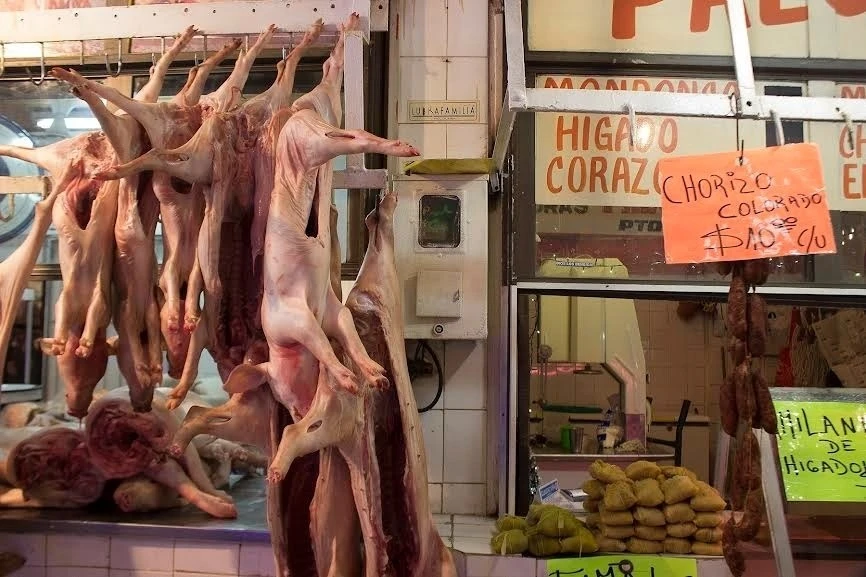 EN EL INTERIOR DEL MERCADO DEL NORTE. La caja de energía contrasta con los lechones colgados, las empanadas y otros productos para la venta.