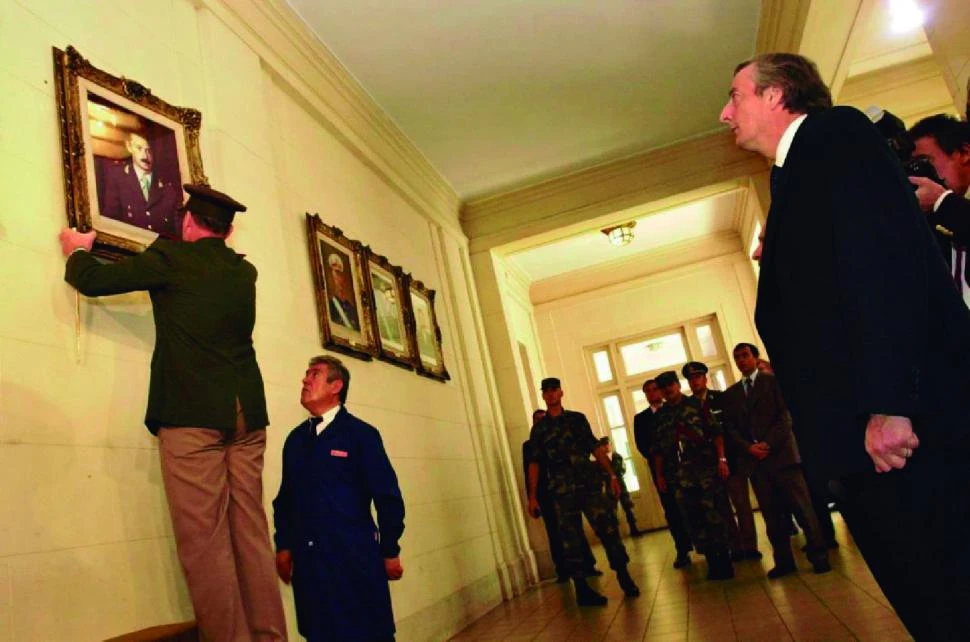 COLEGIO MILITAR, 24/03/2004. Kirchner observa cómo Bendini descuelga el cuadro de Videla.