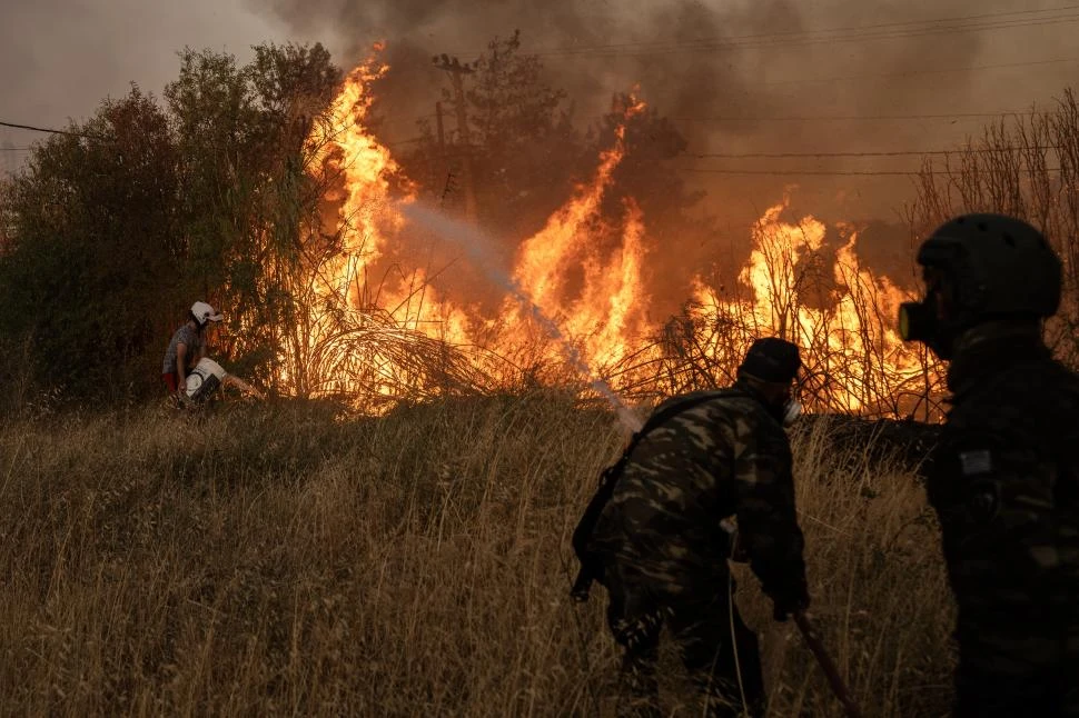 A DESTAJO. Voluntarios trabajan sin descanso cerca de Penteli, un suburbio al noreste de la capital de Grecia.