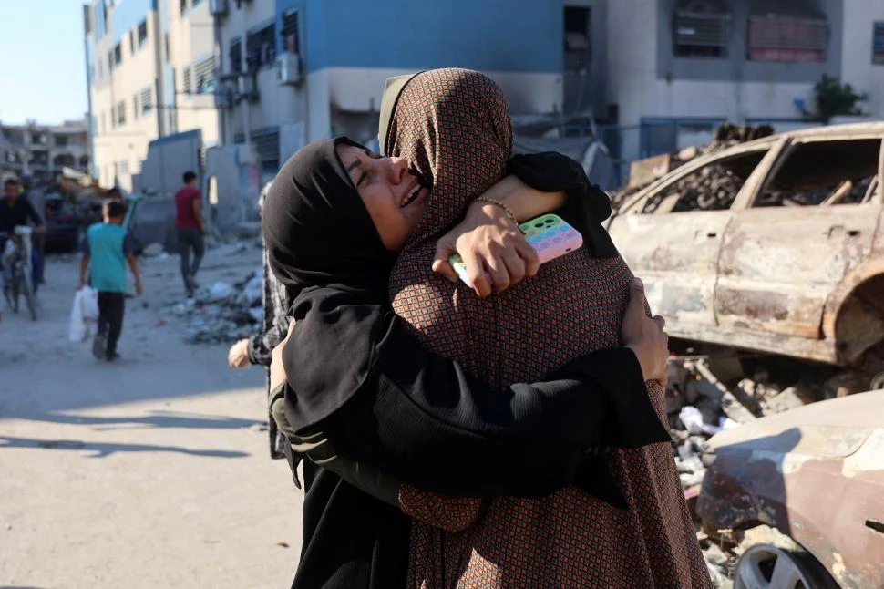 GOLPE. Mujeres palestinas lloran junto a los restos de una escuela destruida en el barrio de Rimal, en Gaza.   