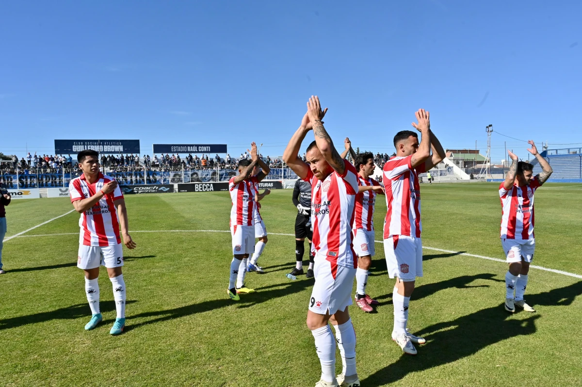 BRAZOS EN ALTO. El plantel saluda al grupo de allegados que ocupó una tribuna del estadio de Guillermo Brown. La fiesta siguió en el vestuario visitante, en donde hubo cánticos y locura luego del agónico triunfo.