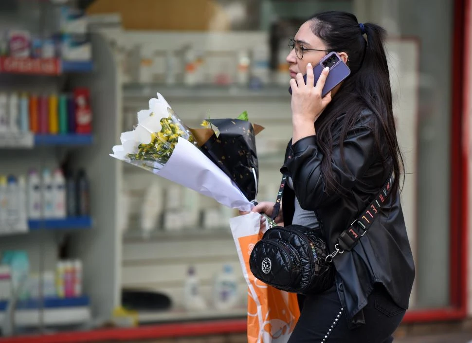 UNA ESCENA QUE SE REPITE. Con flores en una mano y un celular en la otra, ella camina distendida por la zona céntrica de la ciudad. 