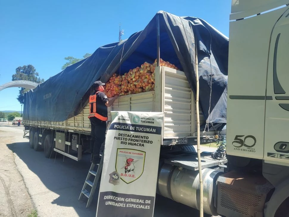 REVISANDO LA CARGA. Un efectivo controla subido en una escalera las bolsas con papa que traslada un camión en el límite con Catamarca.