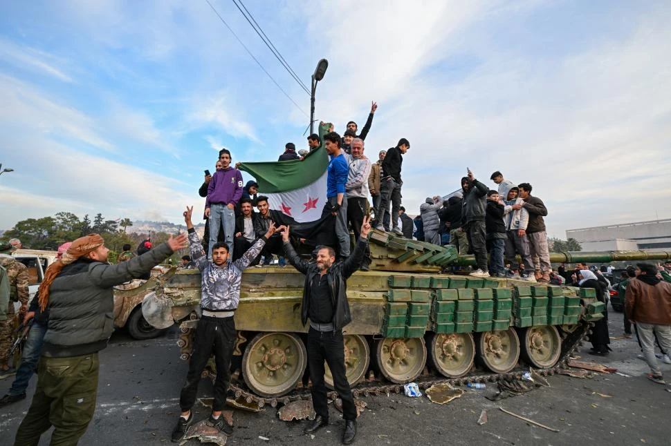 CONTROL DE LA CAPITAL. Ciudadanos saludaron la llegada de los rebeldes a la plaza central de Damasco, luego de la dimisión de Bashar al Asad.   afp