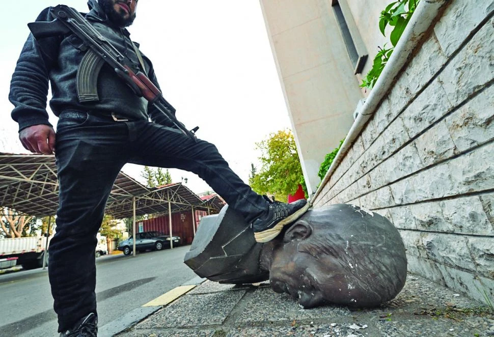 EL FINAL. Un rebelde pisa la cabeza de la estatua del derrocado presidente Bashar Al Asad. afp