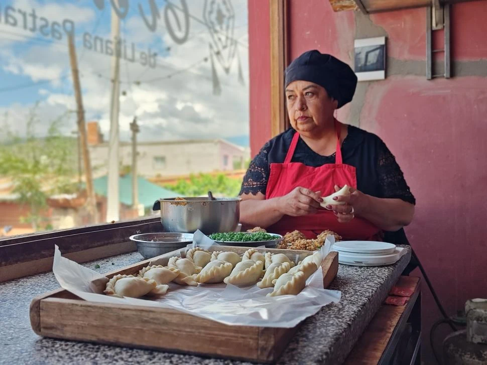 EN ACCIÓN. Liliana Pastrana arma sus empanadas a gran velocidad mientras mira por la ventana de la cocina de su cara, donde instaló su restaurante.