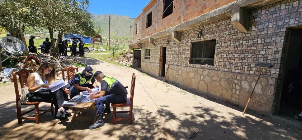 EN PLENO TRABAJO. Una funcionaria judicial y policías analizan en el patio de una vivienda los documentos encontrados en un allanamiento.