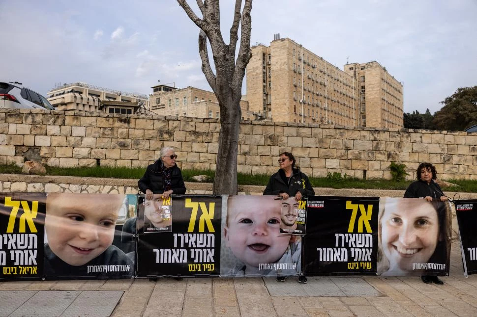 CAMPAÑA. Afiches con las caras de Shiri, Kfir y Ariel Bibas, frente a la oficina de Netanyahu.  afp