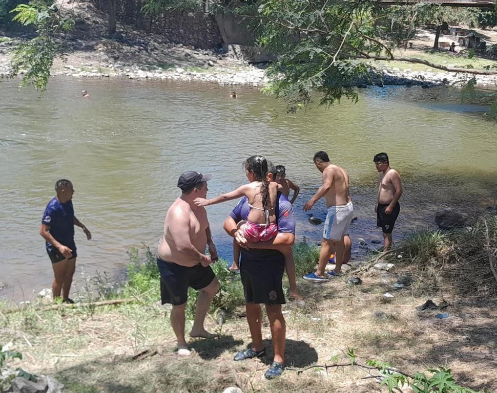 FUERA DE PELIGRO. La niña de siete años en brazos de su padre, luego de ser rescatada por los guardavidas de la Policía en el río Loro. comunicacion publica