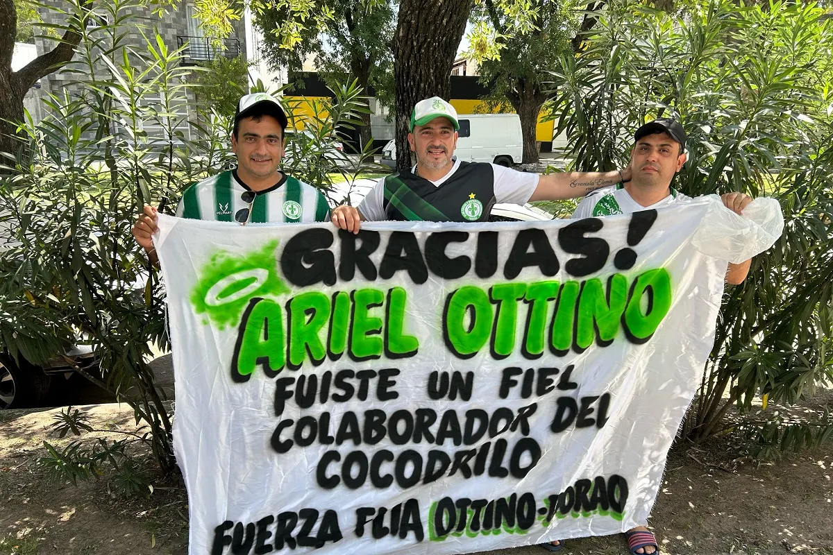 EN FAMILIA. Franco y César Ottino junto a su primo Gustavo González posan con la bandera dedicada a Ariel.