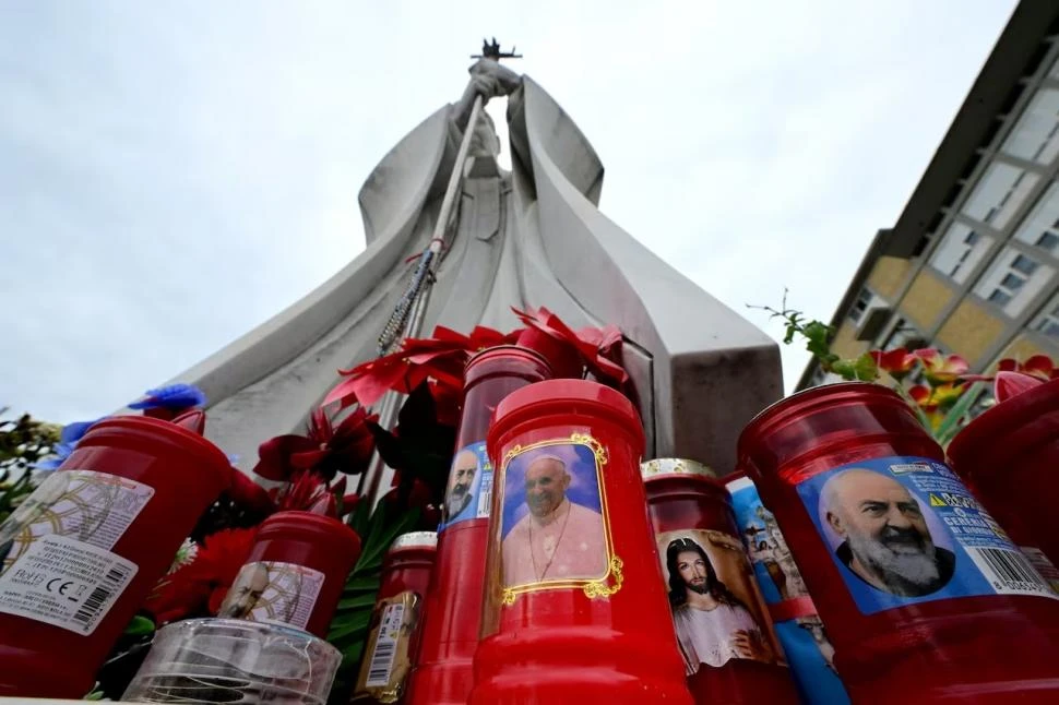 RUEGOS. Ante la estatua de Juan Pablo II en el Hospital Gemelli, los fieles dejan velas para pedir por Francisco.