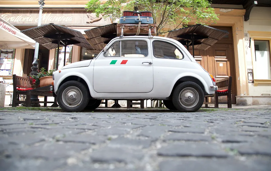 ESCENA ITALIANA. Un Fiat 600 estacionado en una vereda empedrada. / UNSPLASH