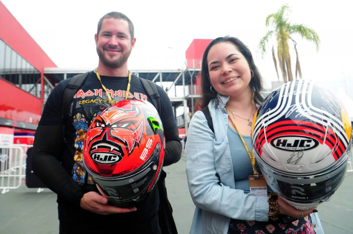 FELICES CON LAS FIRMAS. Mauricio Siri y Constanza Gallardo muestran los cascos en el Paddock del MotoGP.