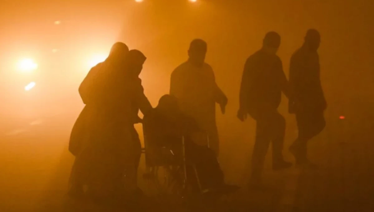 Una persona en silla de ruedas recibe ayuda de otros para cruzar en medio de una gran tormenta de polvo en la ciudad de Basora, al sur de Irak. Foto: AFP/The Express Tribune