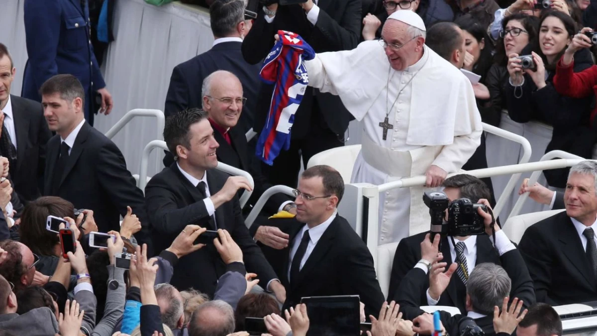 CON LA DEL CICLÓN A TODOS LADOS. Francisco recibe una camiseta de San Lorenzo durante su recorrido en el papa móvil.