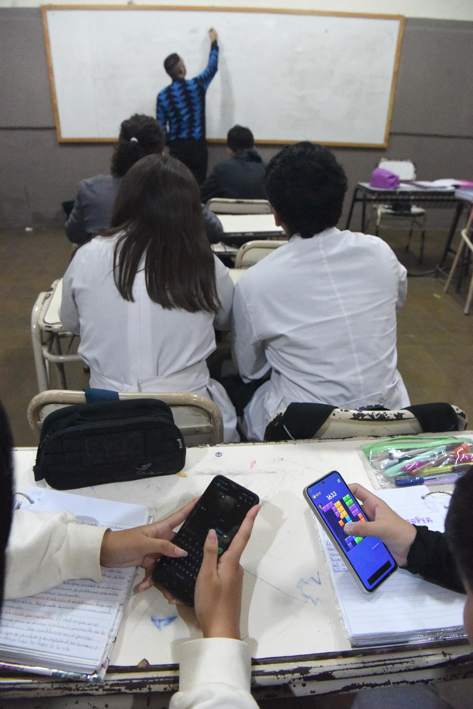 EN SIMULTÁNEO. Mientras el docente da la clase, algunos estudiantes revisan redes sociales o miran videos en sus teléfonos.